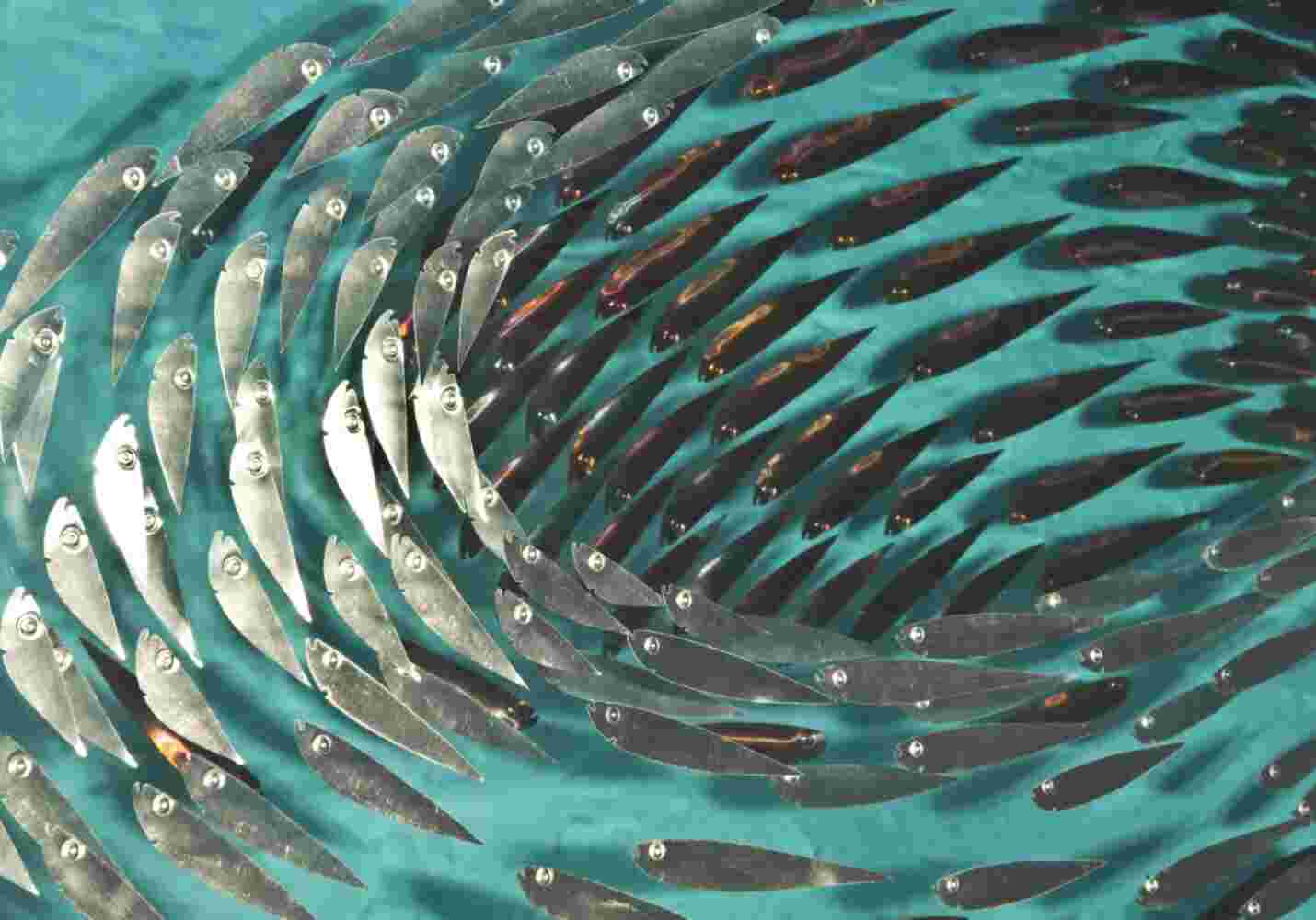 Three-dimensional wall sculpture, school of fish theme, with layers of plexiglass, aluminum frame and swirling metal fish.