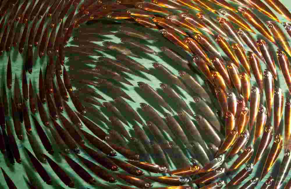 Three-dimensional wall sculpture, school of fish theme, with layers of plexiglass, aluminum frame and swirling copper fish.