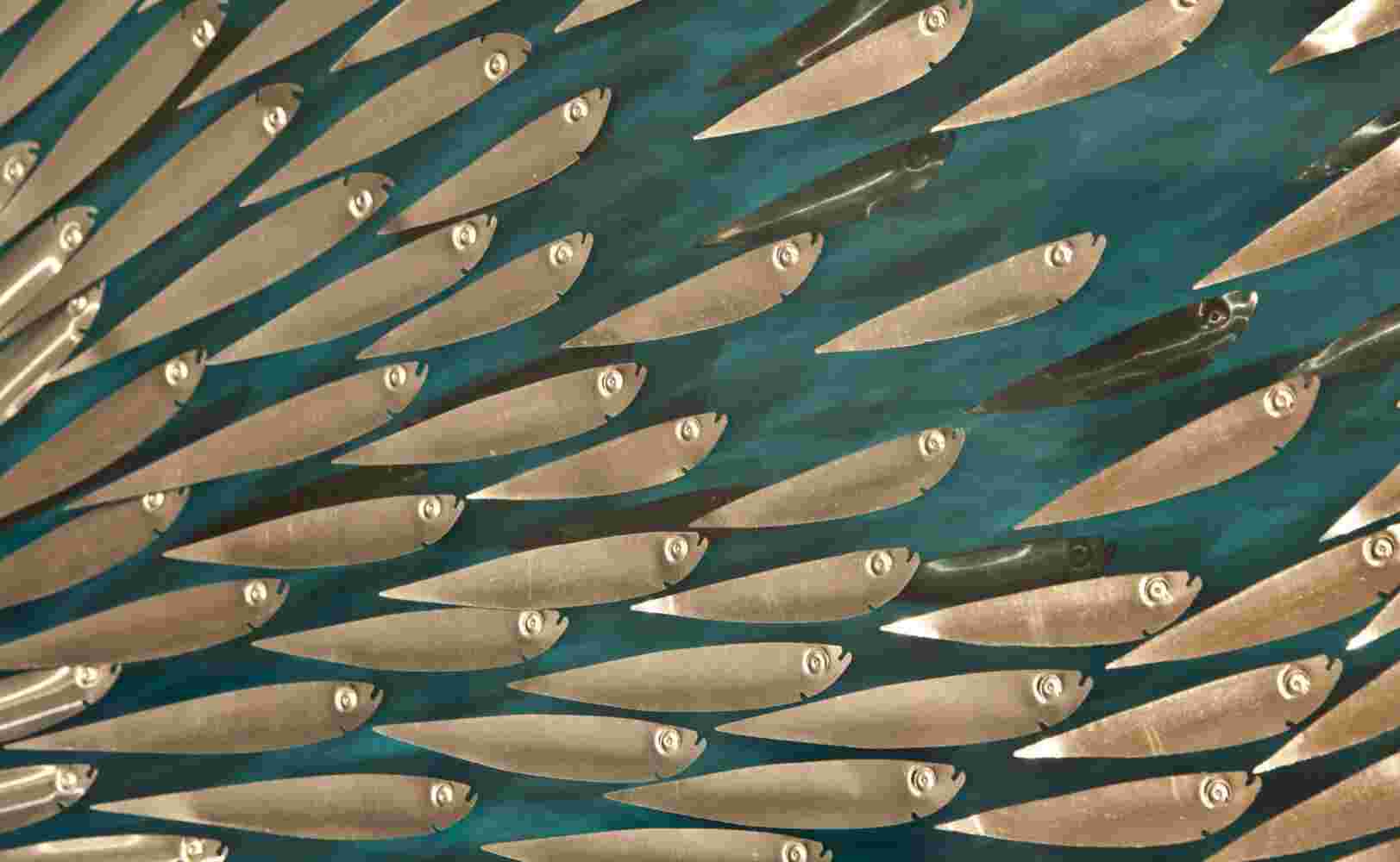 Three-dimensional wall sculpture, school of fish theme, with layers of plexiglass, aluminum frame and explosive copper fish.