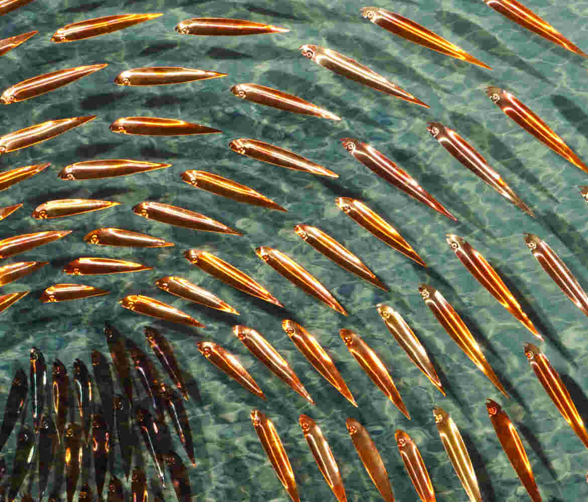 Three-dimensional wall sculpture, school of fish theme, with layers of plexiglass, aluminum frame and a wave of copper fish.