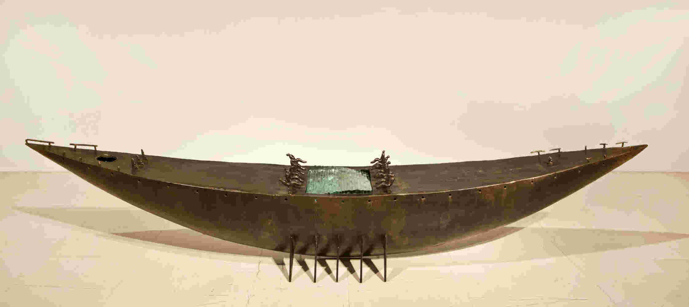 Large scale boat sculpture made of cast bronze and glass with passengers.