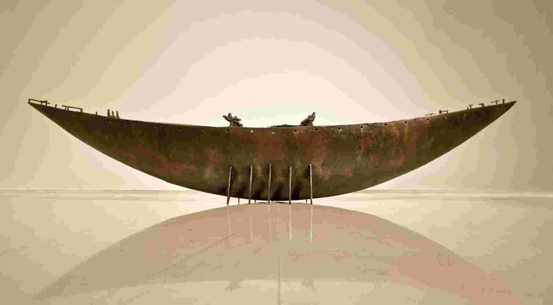 Large scale boat sculpture made of cast bronze and glass with passengers.