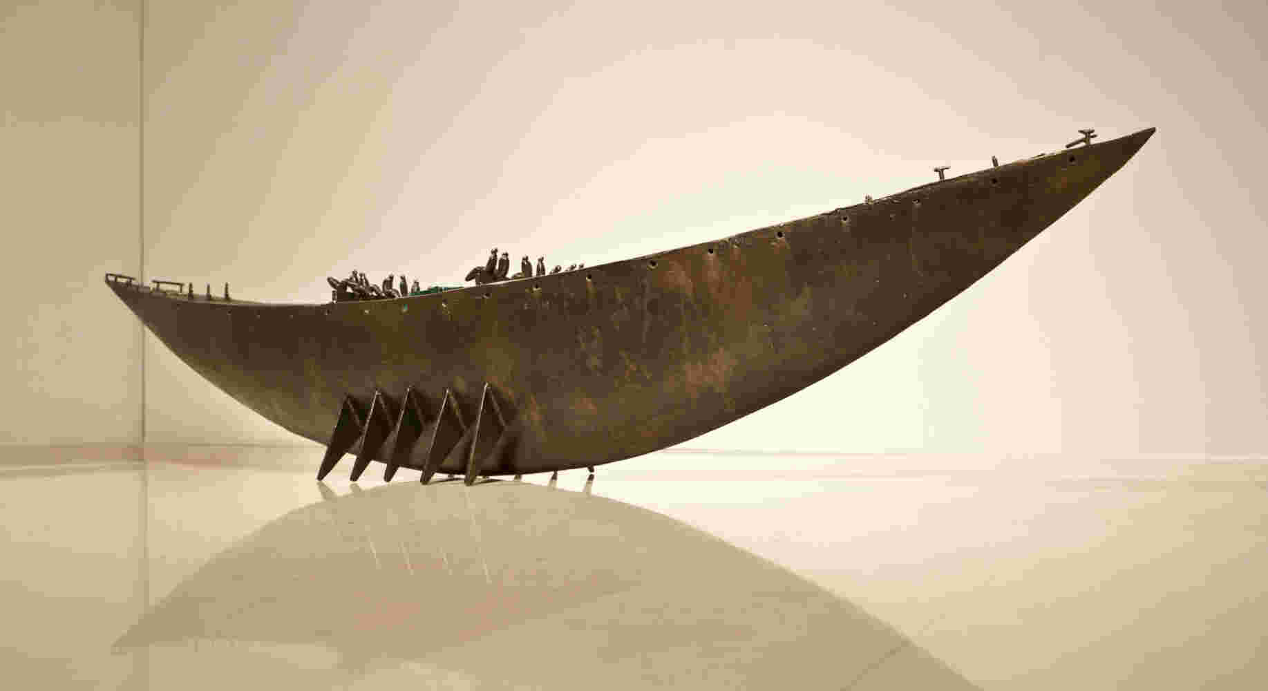 Large scale boat sculpture made of cast bronze and glass with passengers.