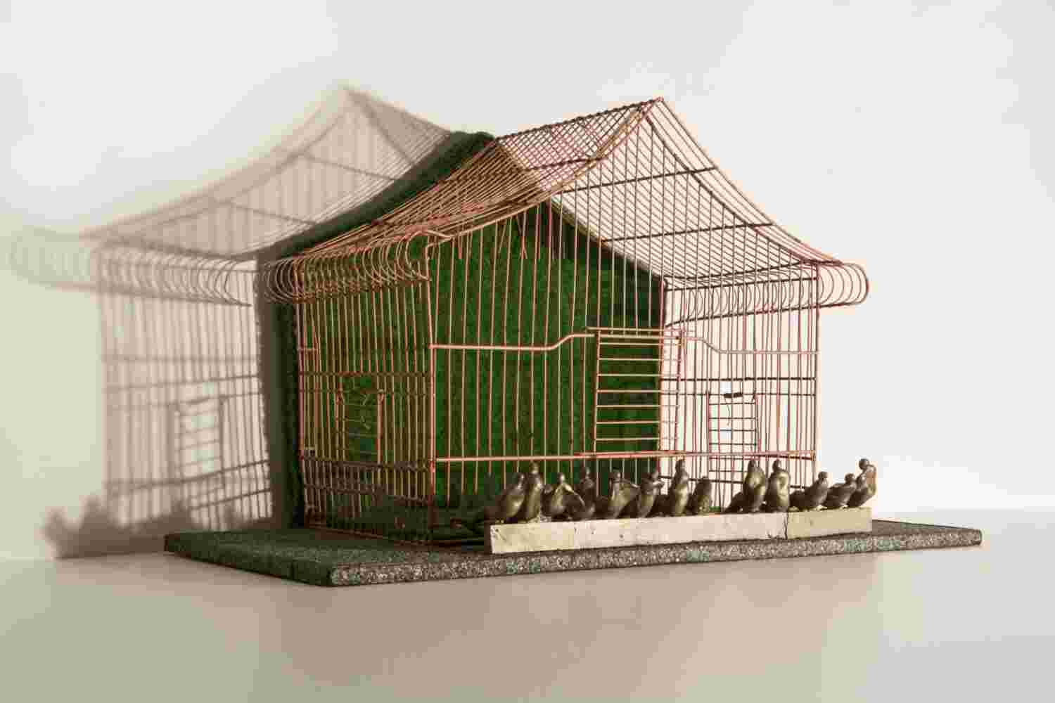 Mixed media wall sculpture of a cage with little people made of bronze