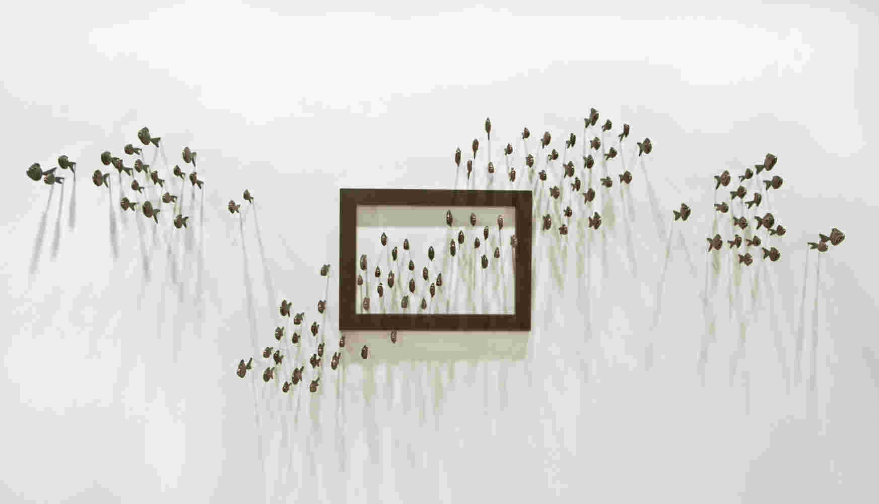 Wall installation of an explosion of fish made of cast bronze and a wooden frame.