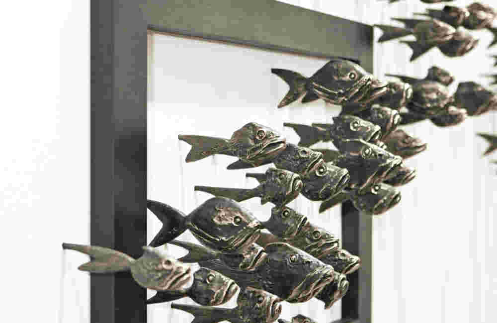 Wall installation of an explosion of fish made of cast bronze and a wooden frame.