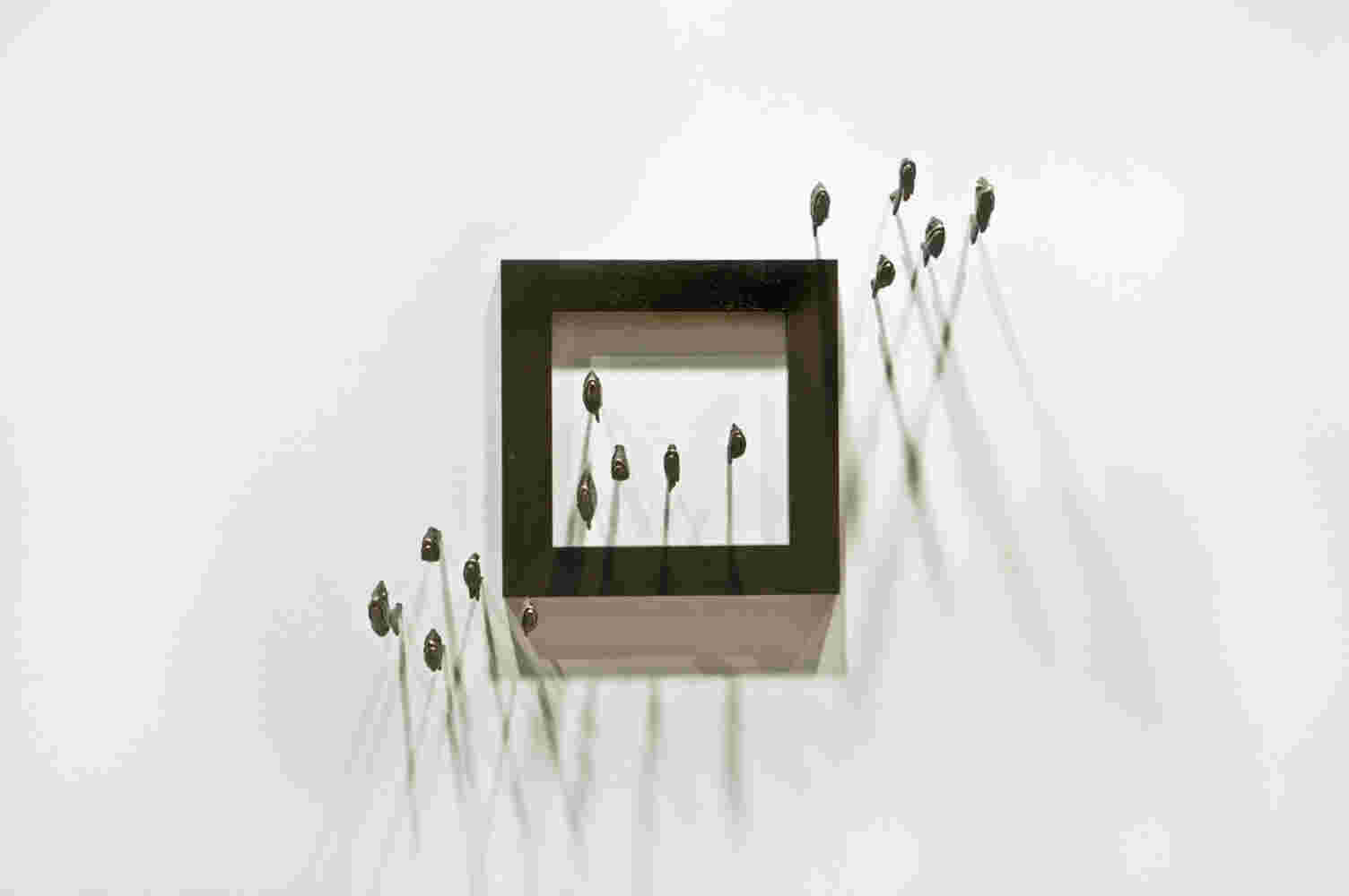 Wall installation of an explosion of fish made of cast bronze and a wooden frame.