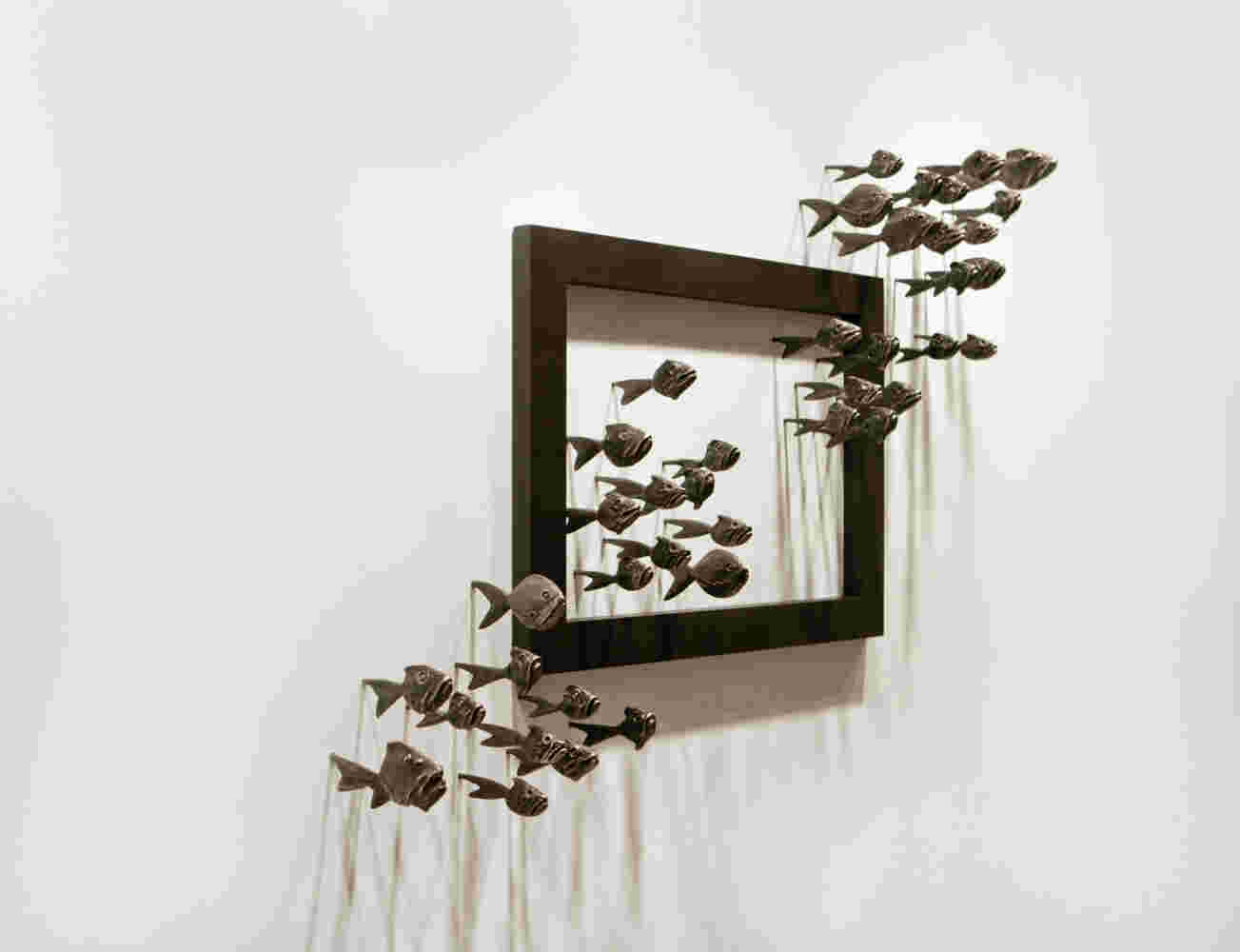 Wall installation of an explosion of fish made of cast bronze and a wooden frame.