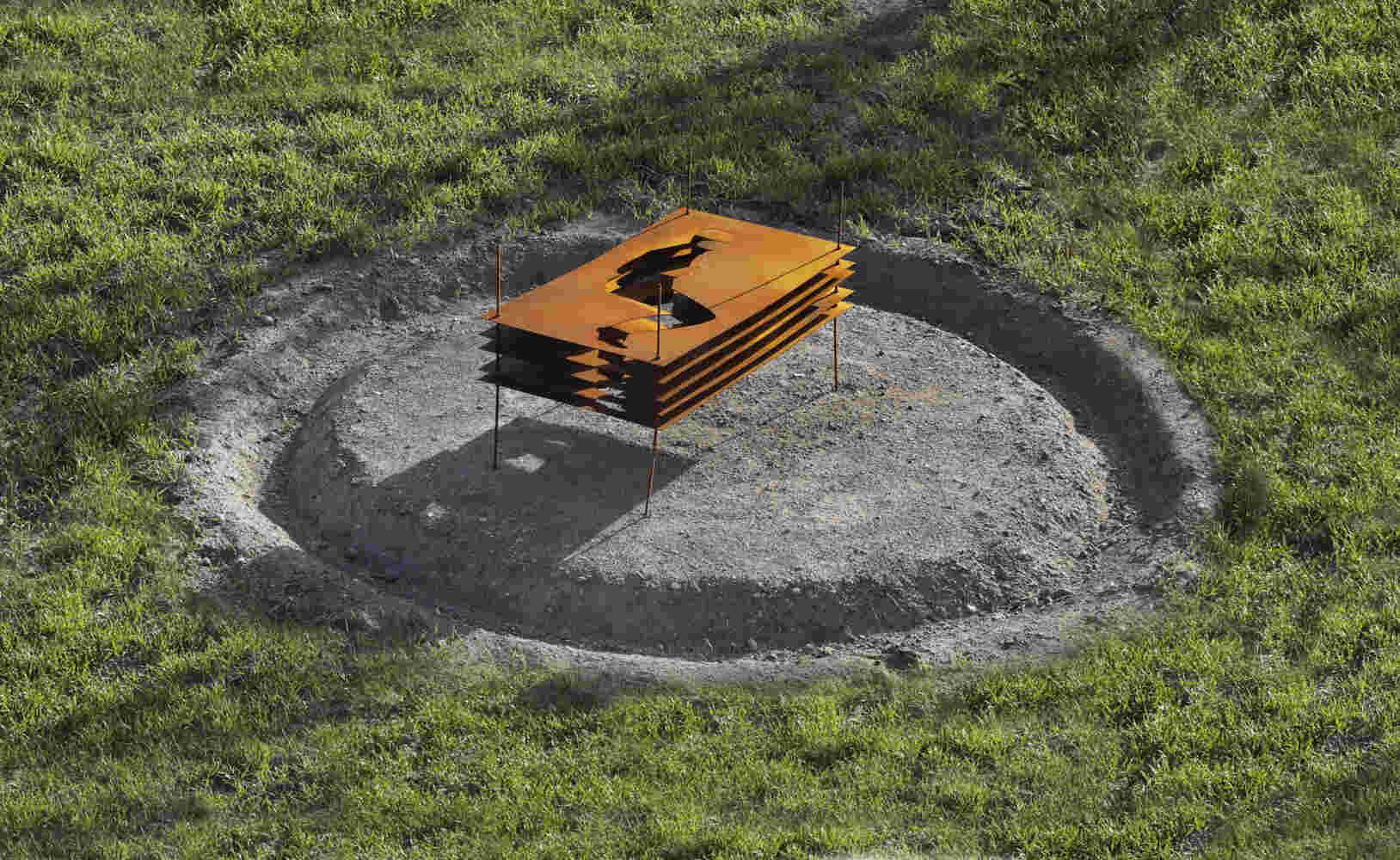 Sculpture made of multiple layers of rusted steel with the shape of a human cut in the middle