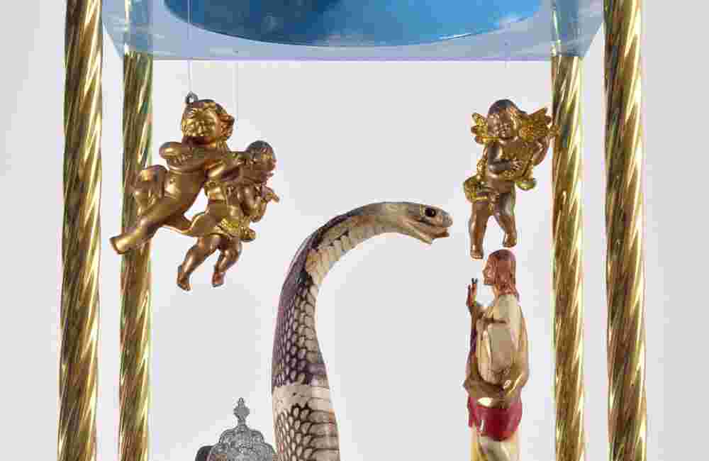 Mixed media sculpture containing a snake, angels and the figure of Christ inside a domed structure with a sky
