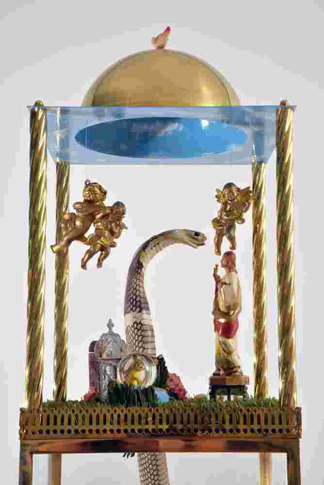 Mixed media sculpture containing a snake, angels and the figure of Christ inside a domed structure with a sky