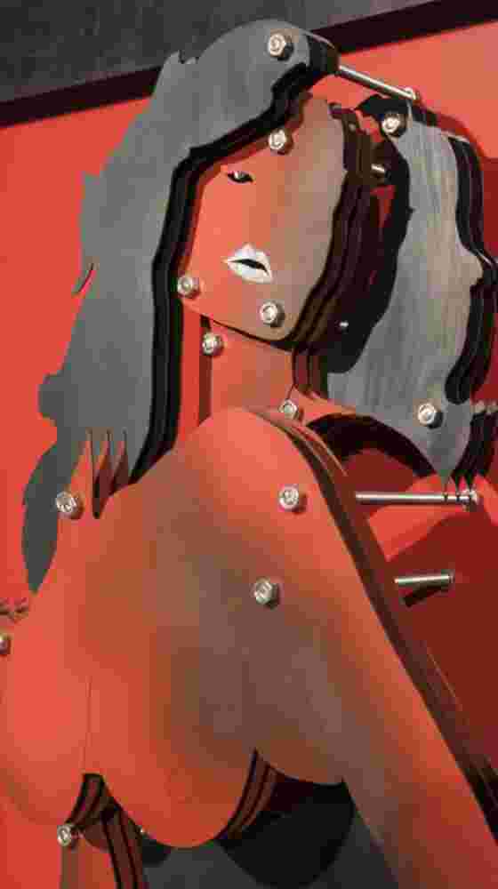 Red wall installation of a woman made of multi layers of black and colored steel.