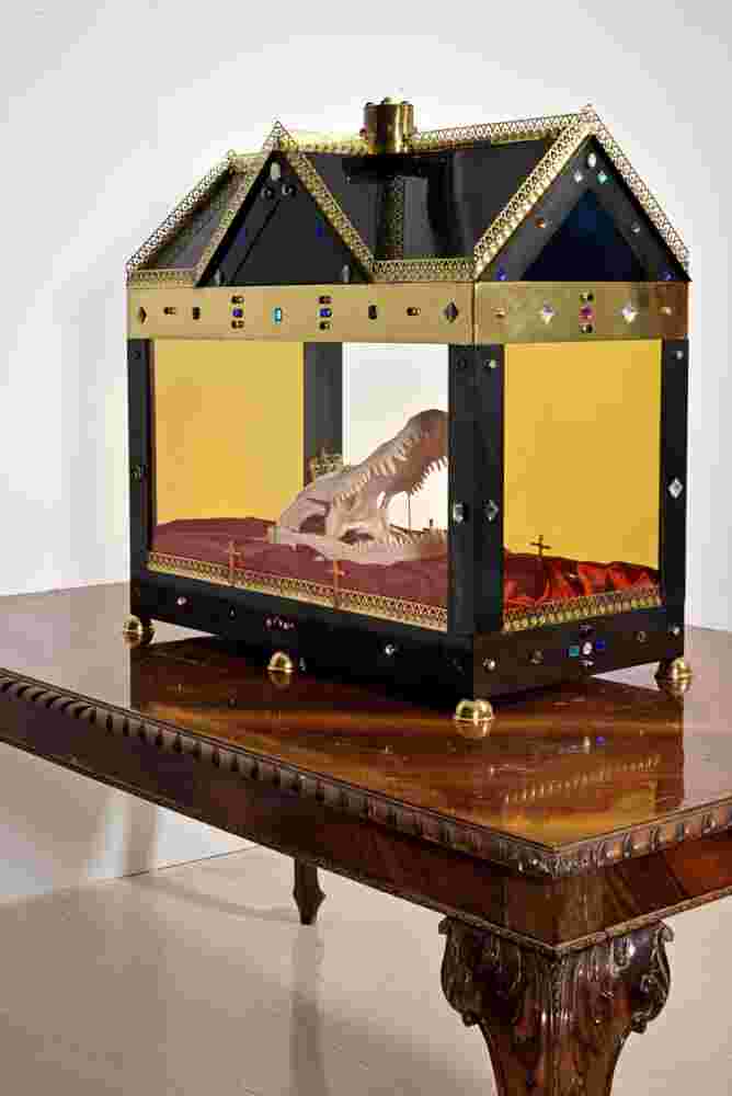Mixed media installation of a crocodile head inside a glass casket on top of a table