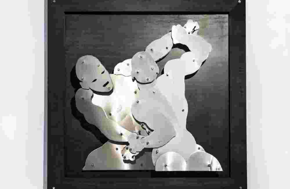 Wall sculpture of two men wrestlers fighting made of steel on black background