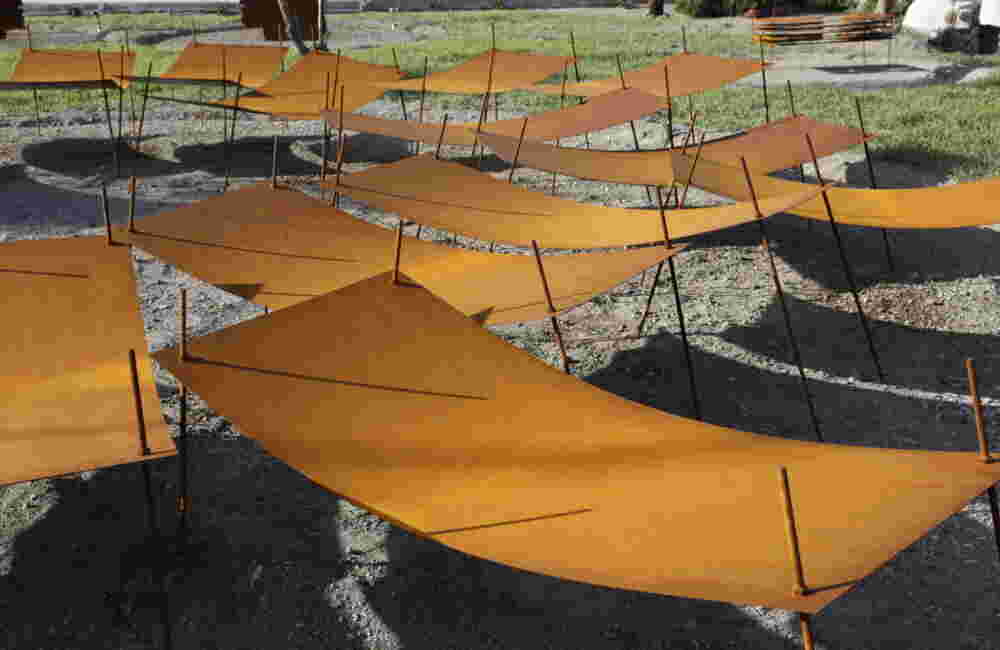 Rusted steel exterior art installation resembling a group of beds gathered together