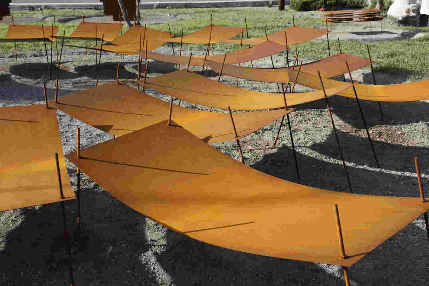 Rusted steel exterior art installation resembling a group of beds gathered together