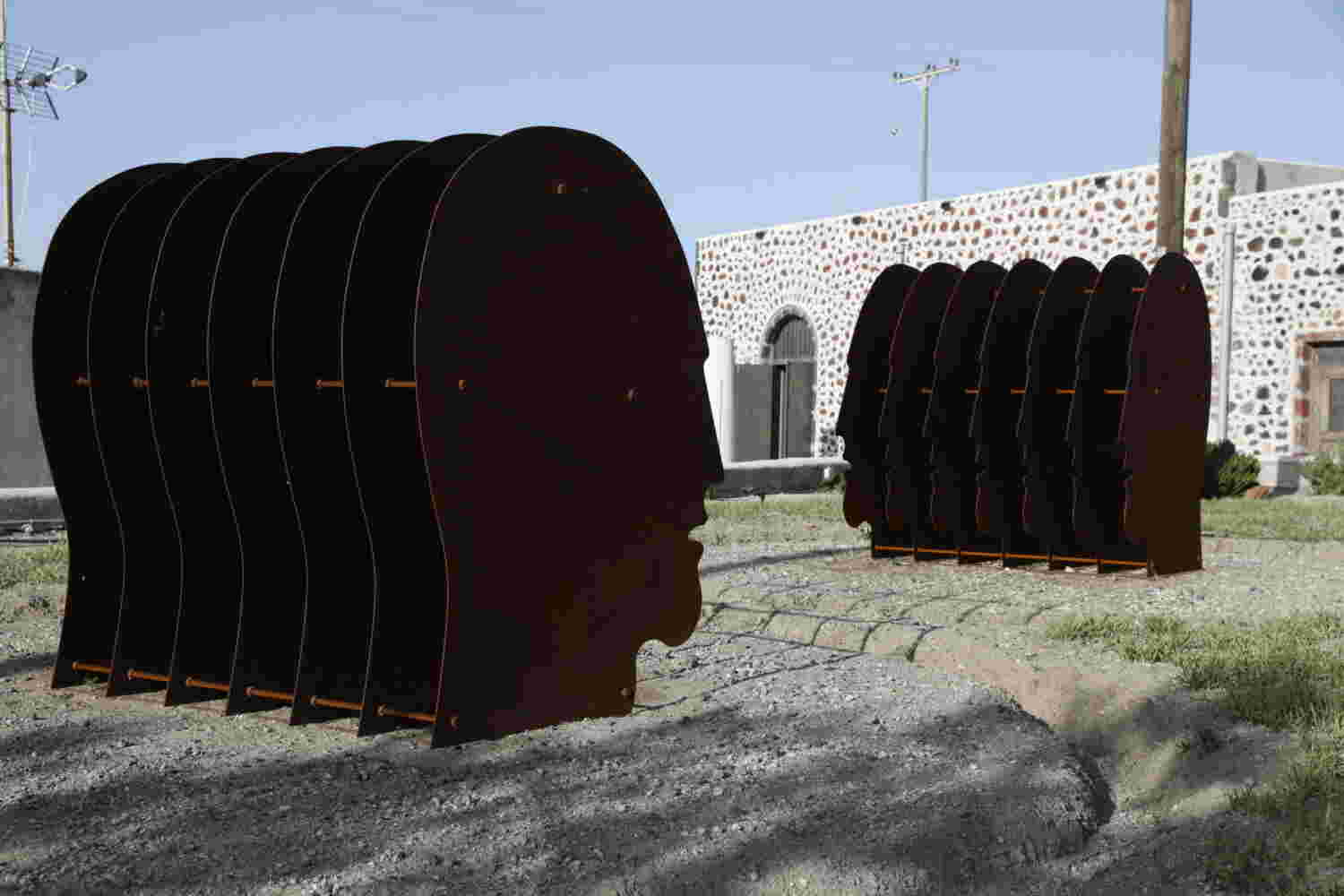 Multiple layers of rusted steel sheets face outdoors sculpture