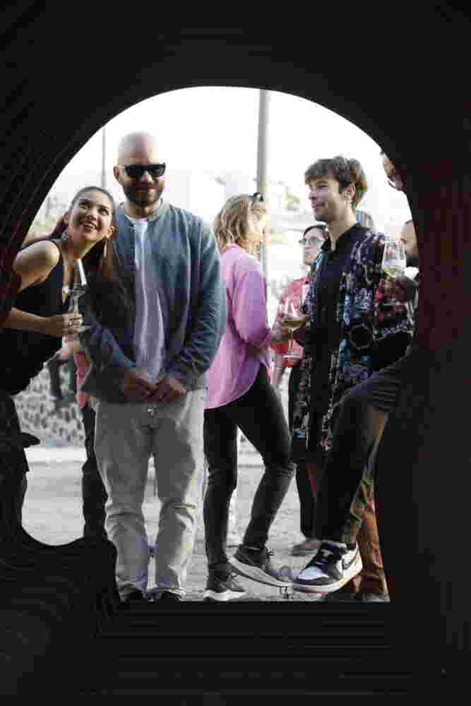 Group of young people happily observing and experiencing a large art installation while drinking wine