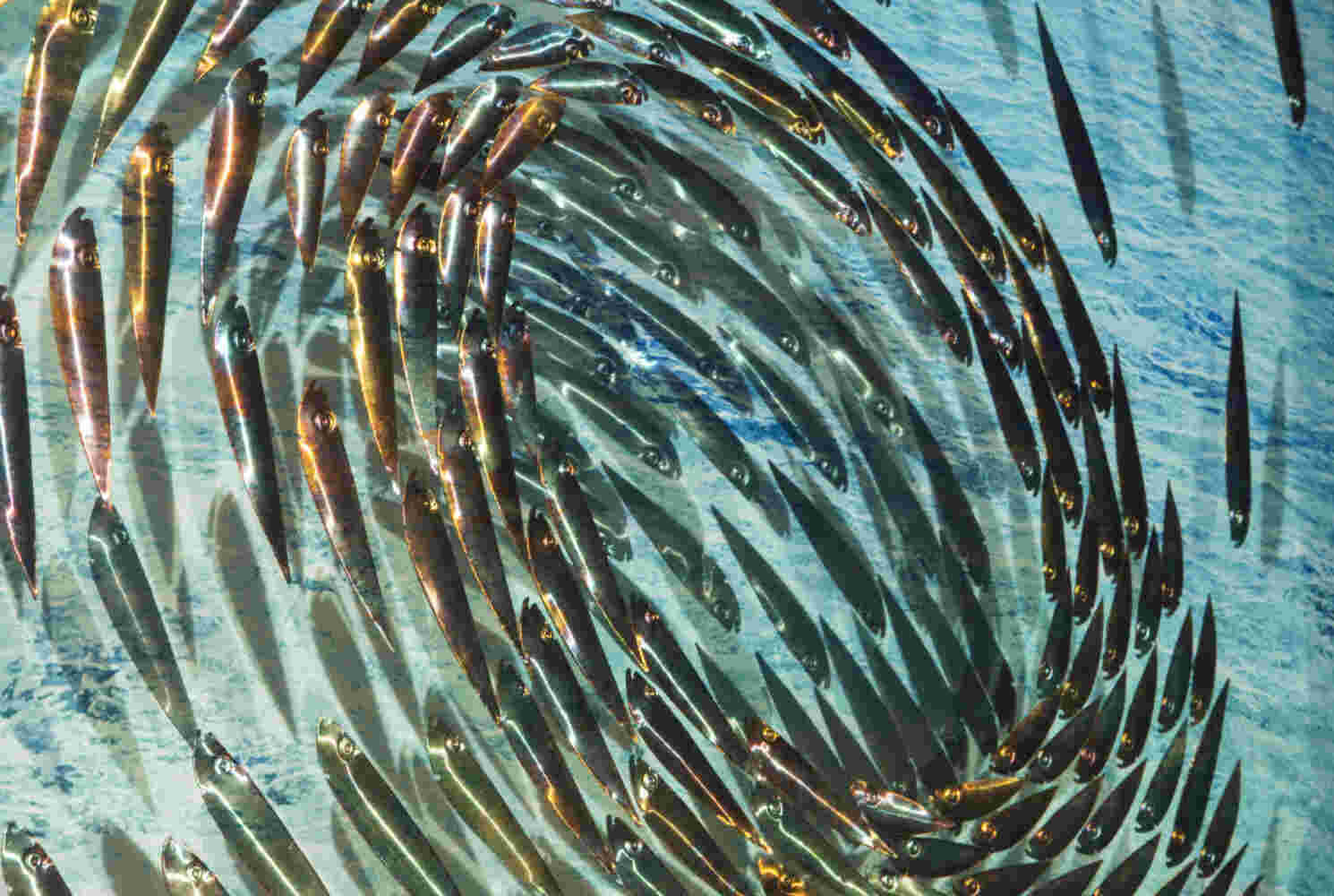 Three-dimensional wall sculpture, school of fish theme, with layers of plexiglass, aluminum frame and swirling copper fish.