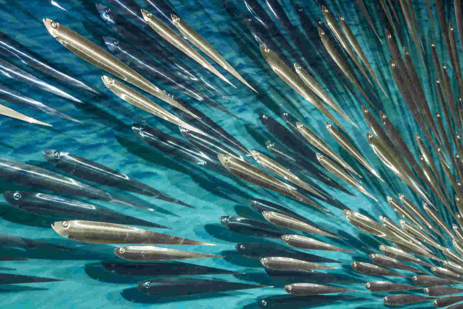 Three-dimensional wall sculpture, school of fish theme, with layers of plexiglass, aluminum frame and swirling copper fish.