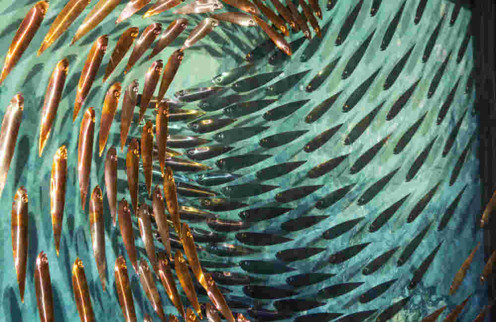 Three-dimensional wall sculpture, school of fish theme, with layers of plexiglass, aluminum frame and swirling copper fish.