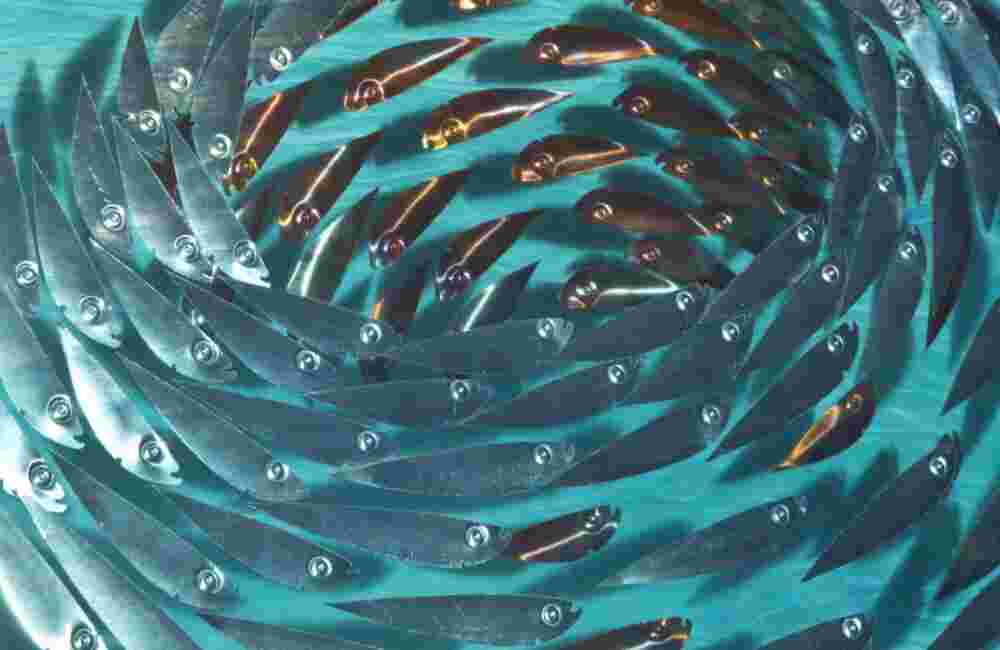 Three-dimensional wall sculpture, school of fish theme, with layers of plexiglass, aluminum frame and swirling copper fish.