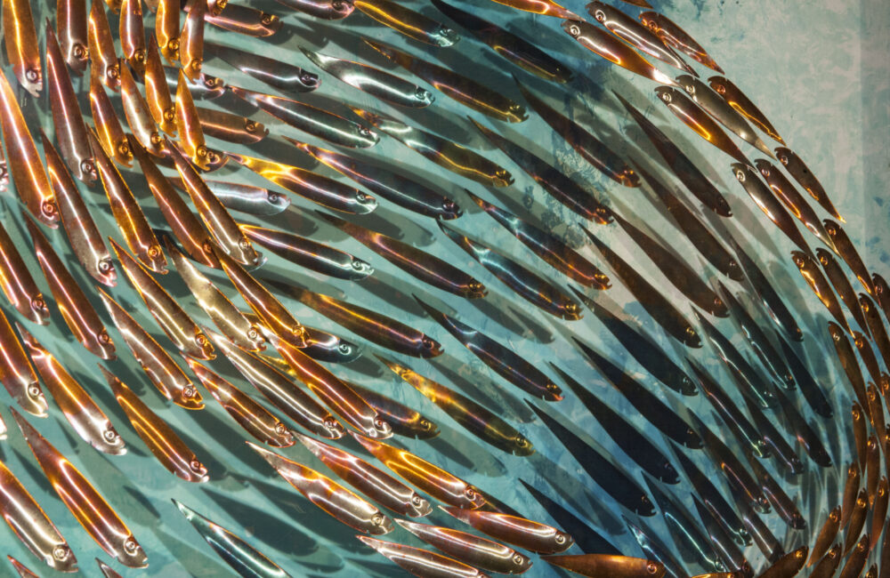 Three-dimensional wall sculpture, school of fish theme, with layers of plexiglass, aluminum frame and swirling copper fish.