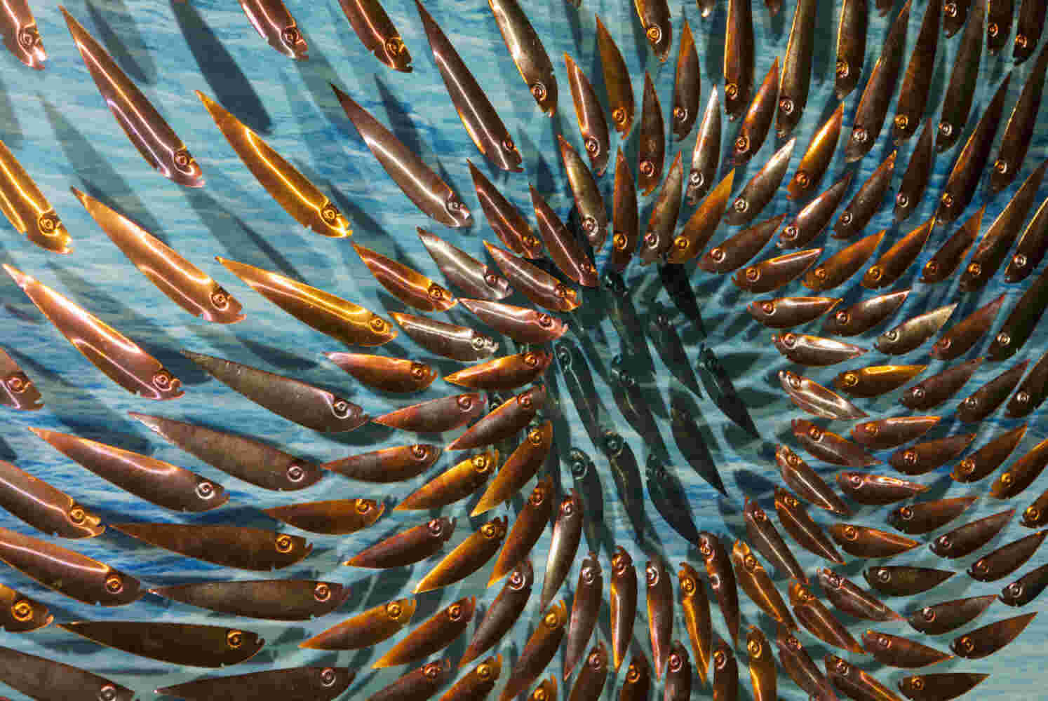 Three-dimensional wall sculpture, school of fish theme, with layers of plexiglass, aluminum frame and swirling copper fish.